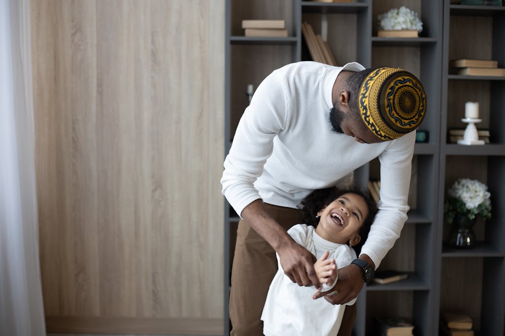 Cheerful black father having fun with cute daughter