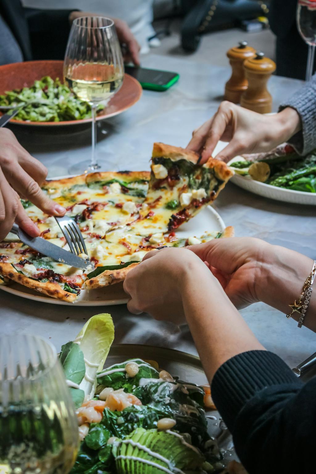 Hands around Pizza on Table