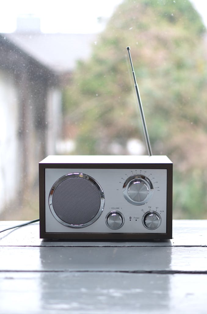A classic radio with antenna on a wooden windowsill in a serene setting.