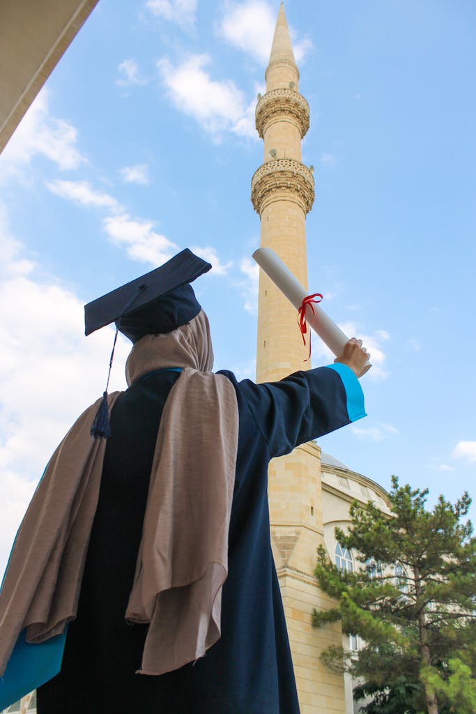 A graduate celebrating with diploma near a mosque tower.