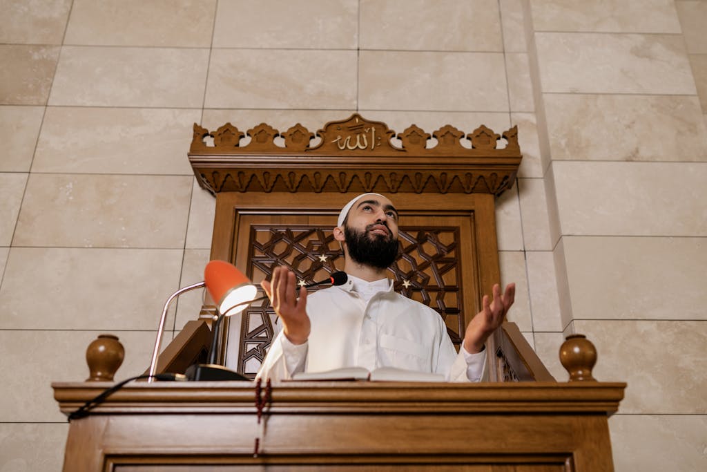 An imam leading prayer from a mosque minbar, symbolizing Muslim faith and tradition.