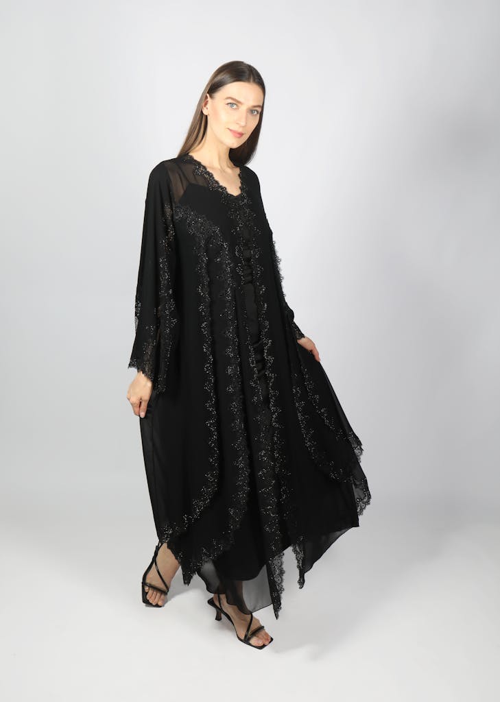 Elegant woman modeling a black abaya in a Dubai studio setting, showcasing traditional fashion.