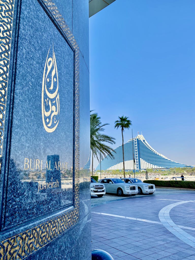 Stunning shot of Burj Al Arab with luxury cars and palm trees in Jumeirah, Dubai.