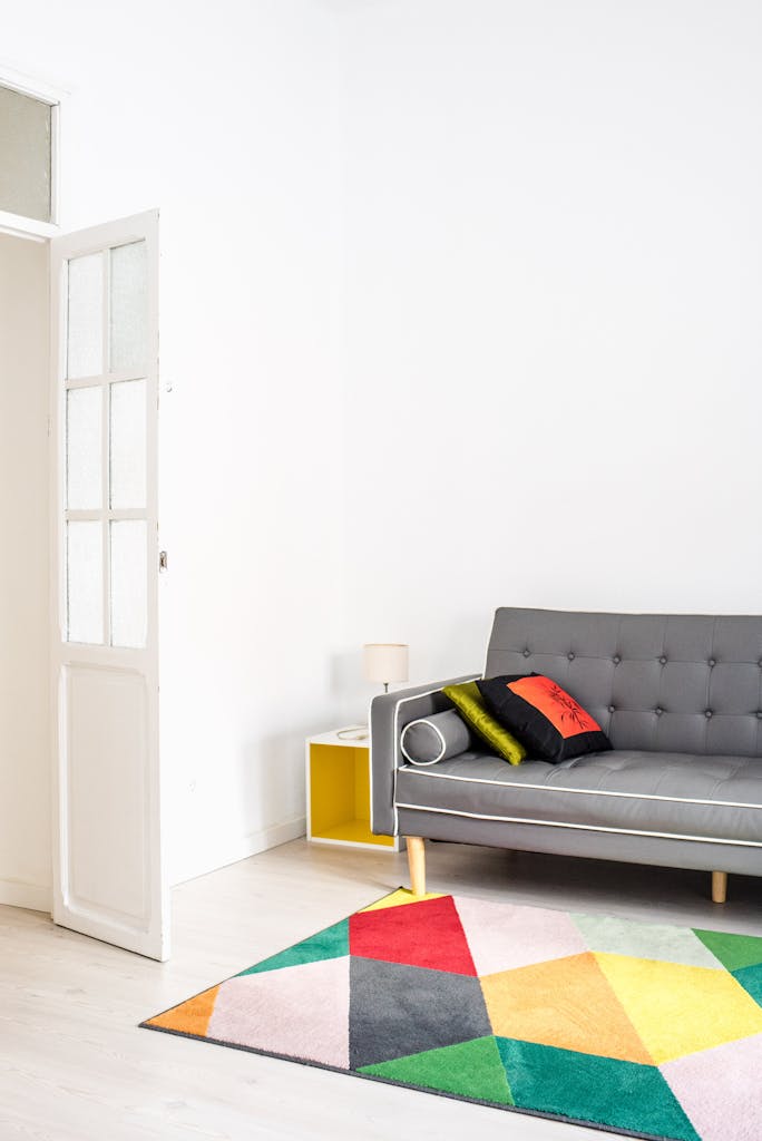 Stylish minimalist living room featuring a colorful geometric rug and a cozy grey sofa for a chic home interior.